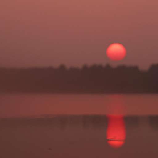 view of a lake during the sunset, red tint, partially covered with fog, blurred background, sun touching the horizon.
